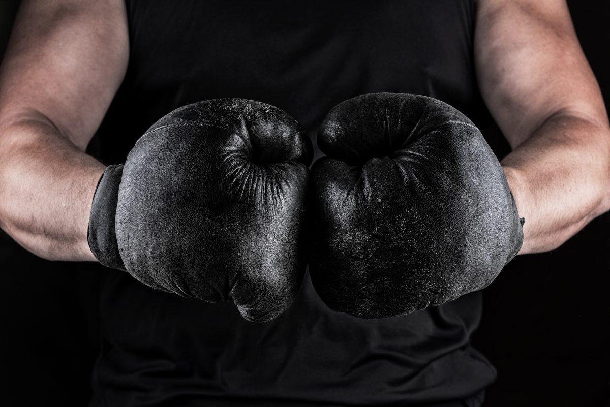 hands of an athlete in black old sport boxing gloves, black background