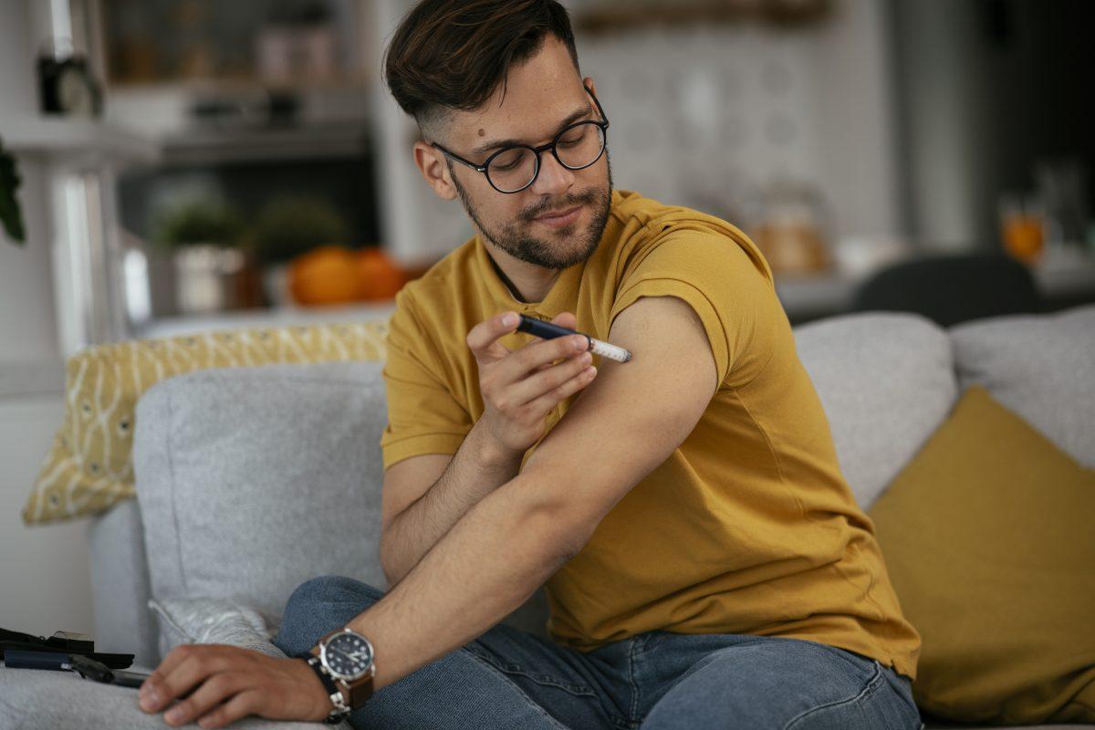 Young man giving himself an insulin shot at home.