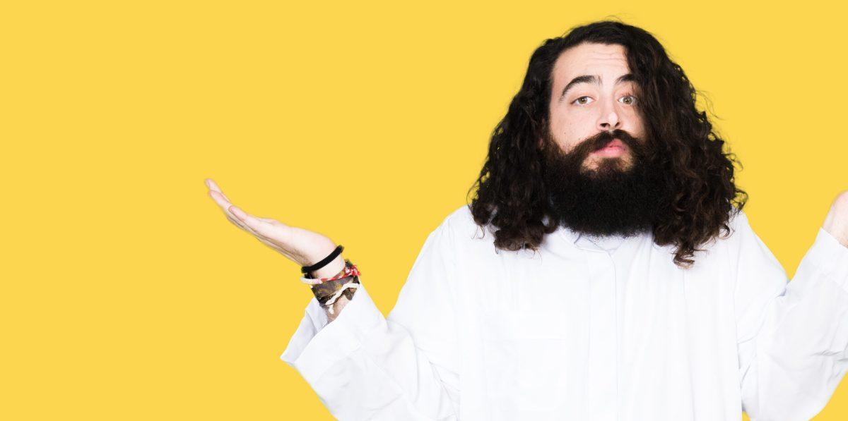 Man wearing Jesus Christ costume clueless and confused expression with arms and hands raised. Doubt concept.