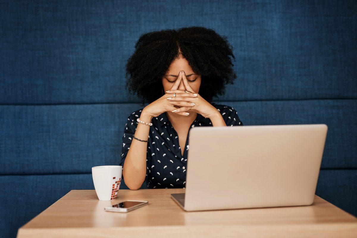 Shot of a young female designer looking stressed while trying to work on her laptop at the office