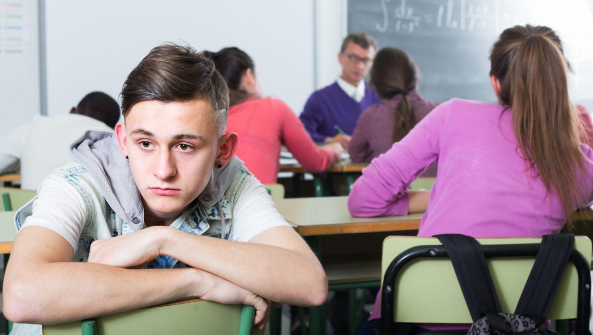 ï»¿lonely school boy sitting away from classmates and feeling depressed  indoor