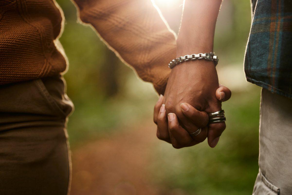 Close up of unrecognizable African American couple holding hands in nature.