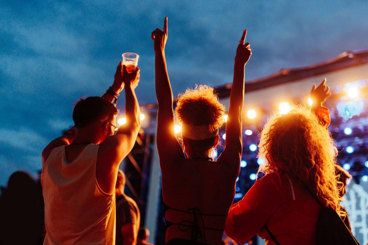 Young happy friends on a music concert at night.